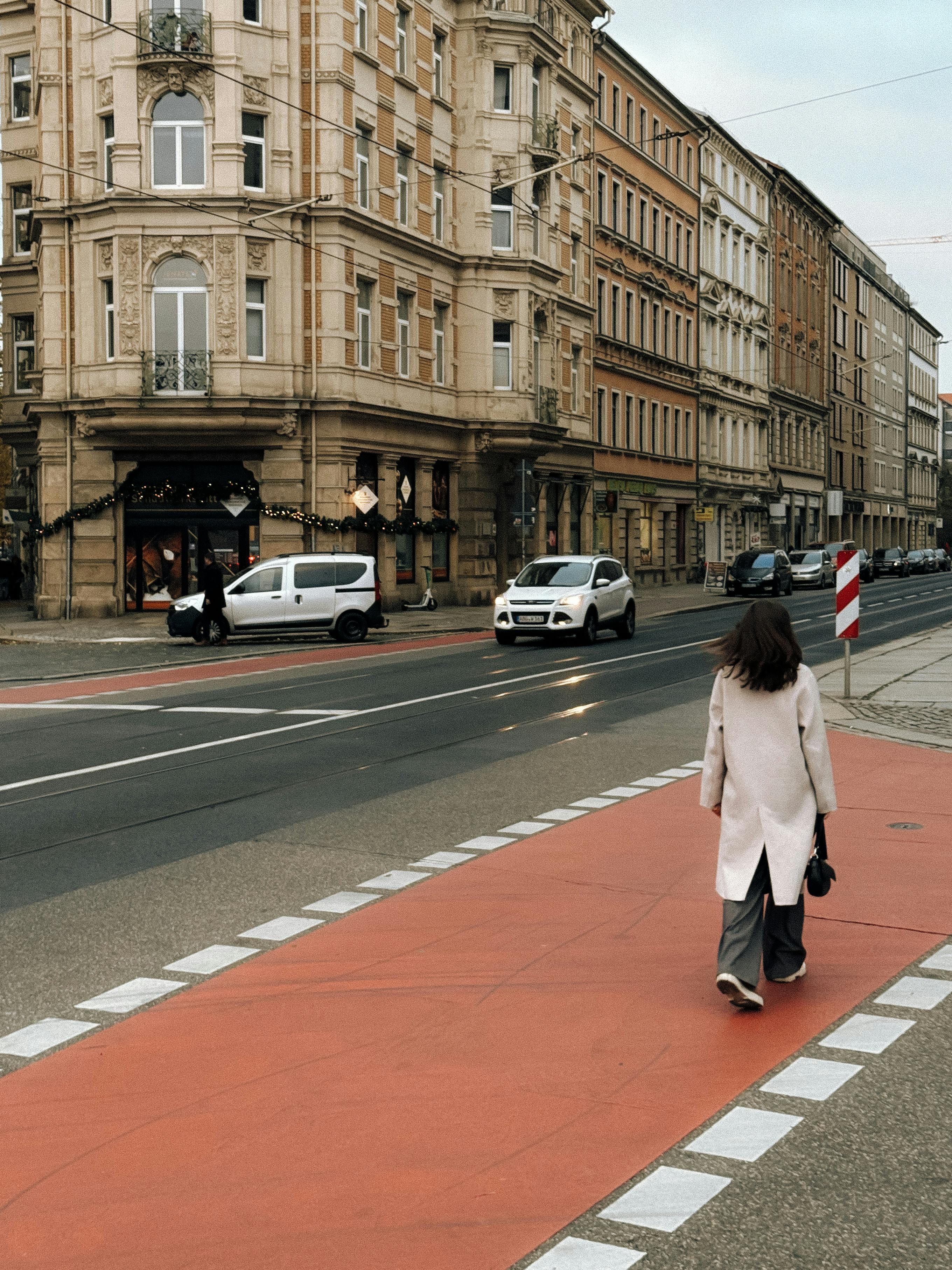 A woman walks along a street in Dresden, Germany, showcasing historic architecture and urban life.