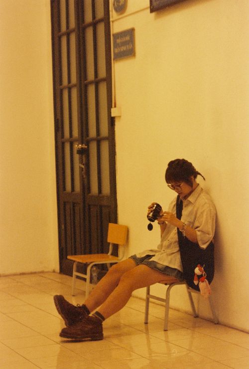 Free Teenager relaxing indoors, examining a camera in a vintage ambiance. Stock Photo