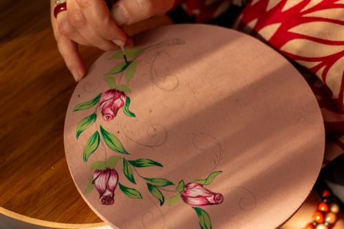 Free Close-up of a hand painting pink flowers on a wooden surface, showcasing artistic craftsmanship. Stock Photo
