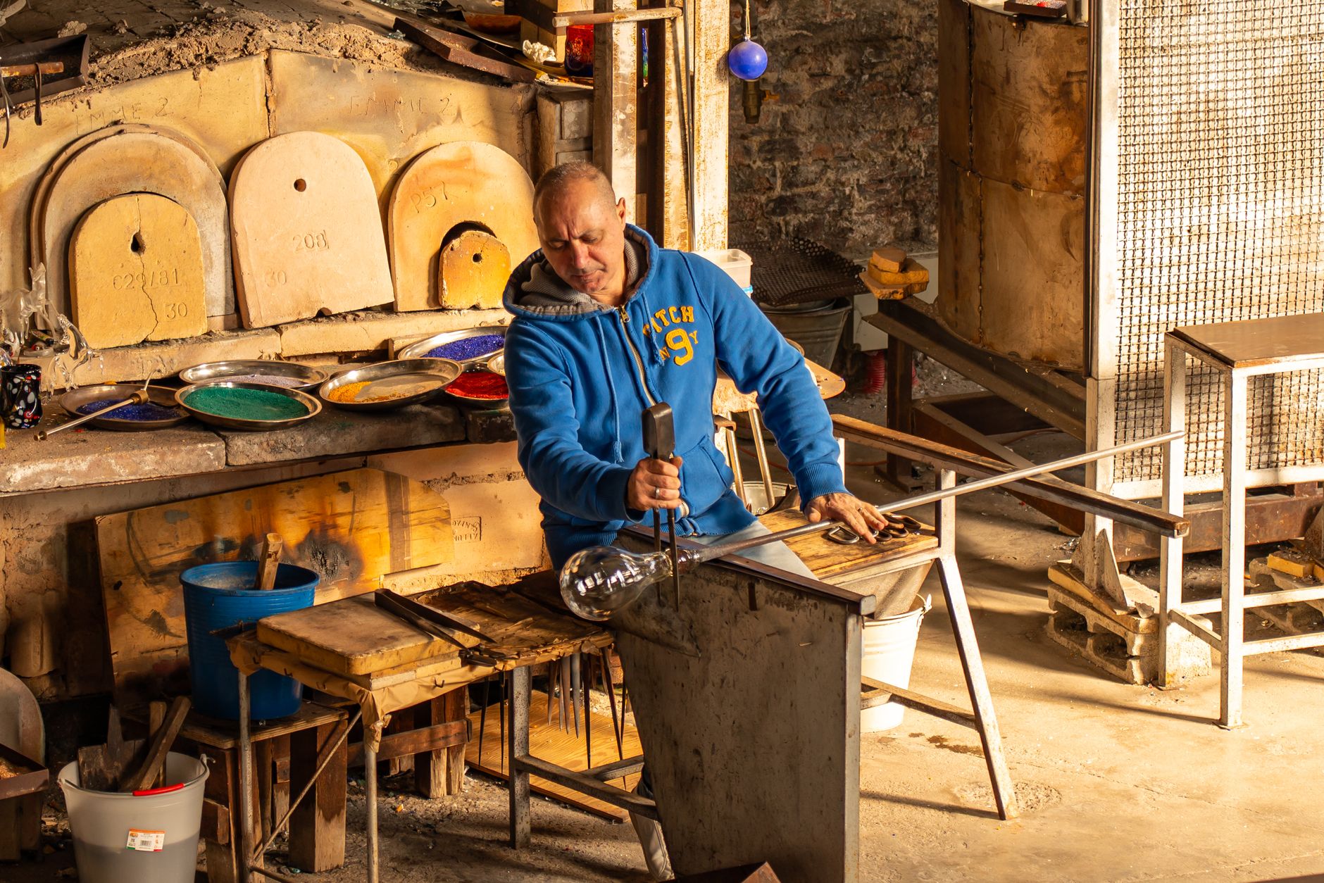 Glassmaker shaping molten glass in a traditional workshop in Venice, Italy, showcasing artisanal craftsmanship.