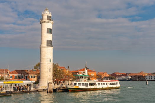 Afternoon view of a ferry passing by the historic lighthouse on Murano Island, Venice, Italy.