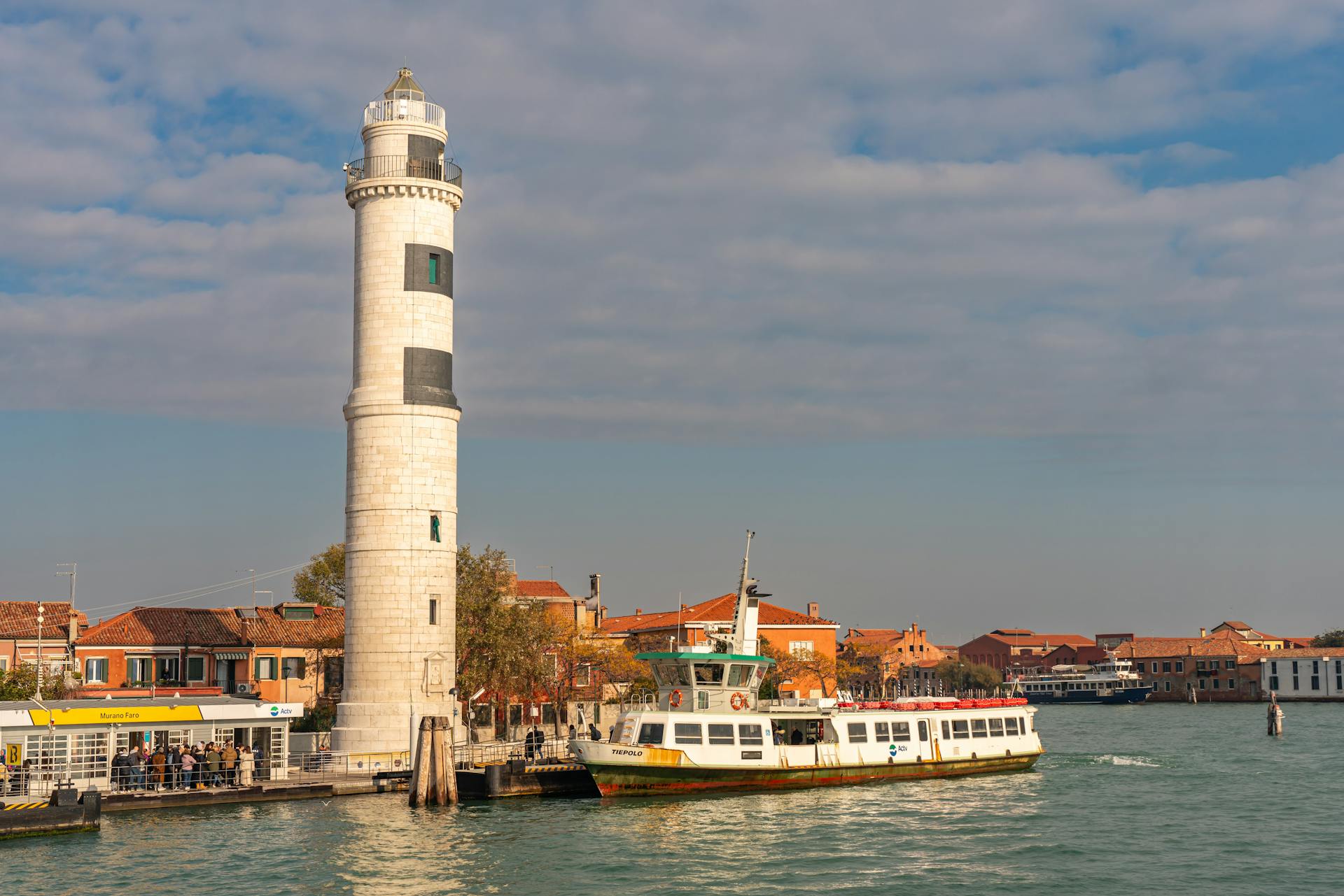 Afternoon view of a ferry passing by the historic lighthouse on Murano Island, Venice, Italy.