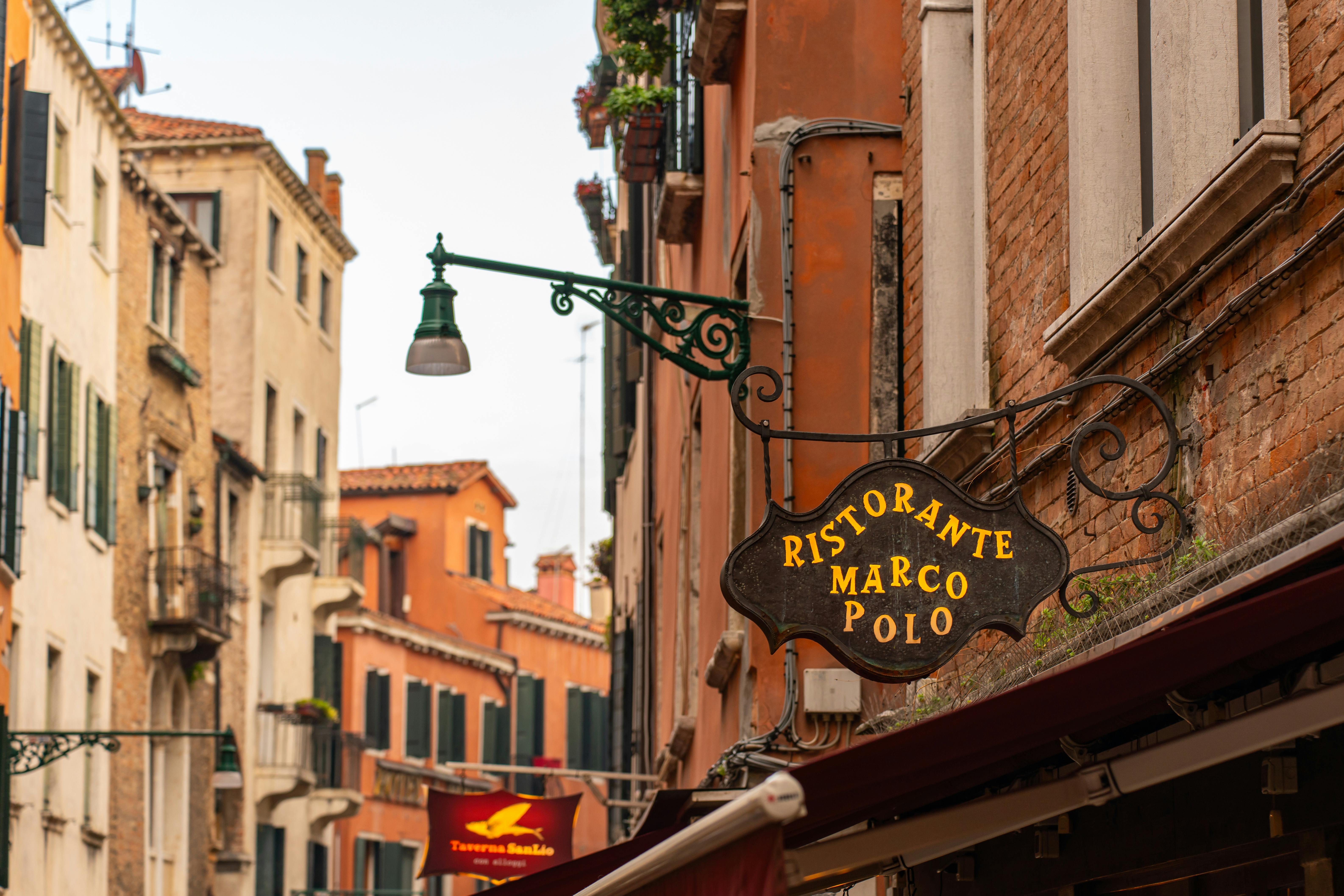 A scenic view of a Venetian street with a classic ristorante sign, capturing the essence of Venice's architecture and charm.