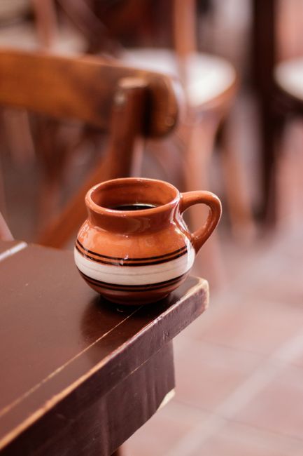 A close-up of a Mexican coffee cup made from earthenware on a wooden table.