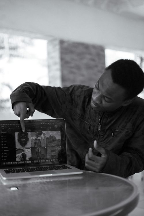 Free Black and white photo of a man pointing to a laptop screen indoors in Nigeria. Stock Photo