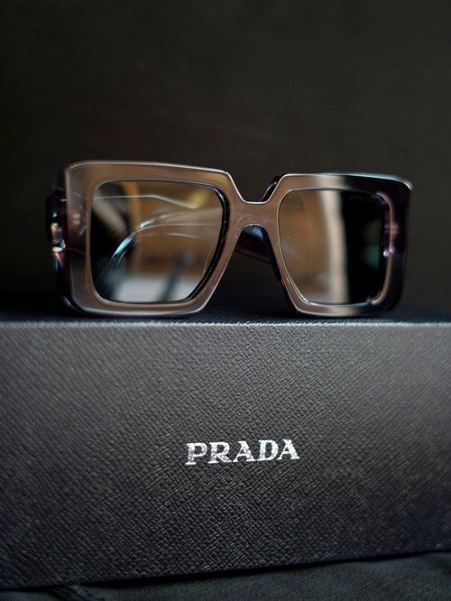 Free Elegant Prada sunglasses showcased on a branded box, ideal for fashion lovers. Stock Photo