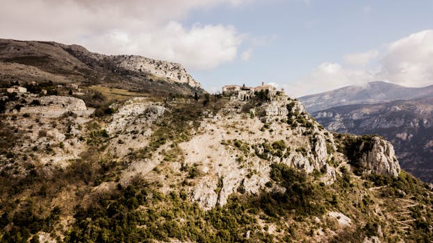 A breathtaking view of rocky cliffs and a village perched atop in France, captured in natural light.