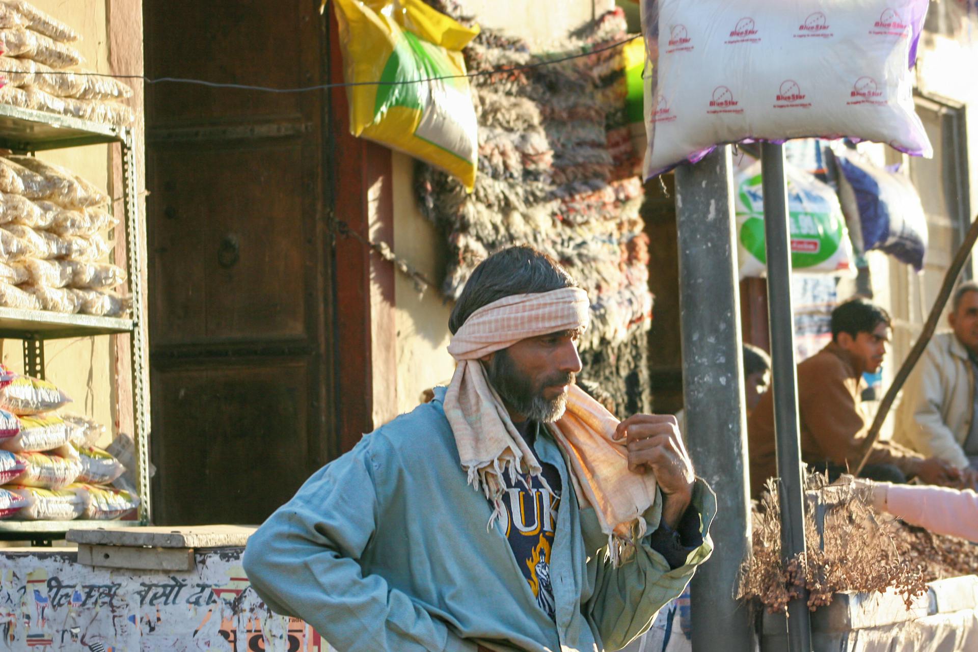 A local street vendor in a lively Indian market surrounded by goods and people.