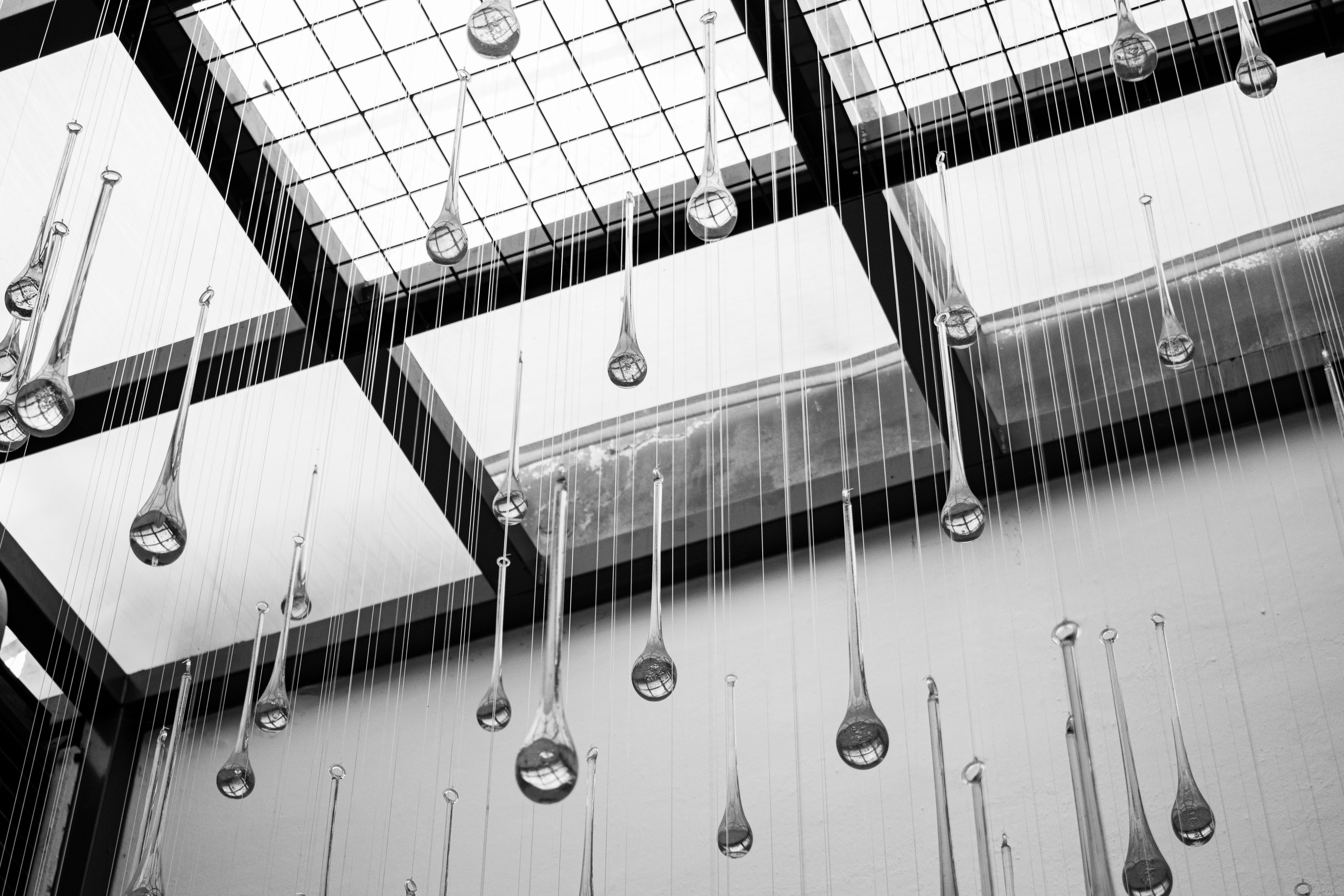 Abstract black and white photo of hanging glass sculptures in a modern atrium ceiling.