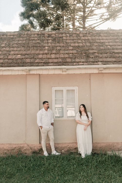 Free A couple poses beside a rustic house with a serene, vintage feel. Stock Photo