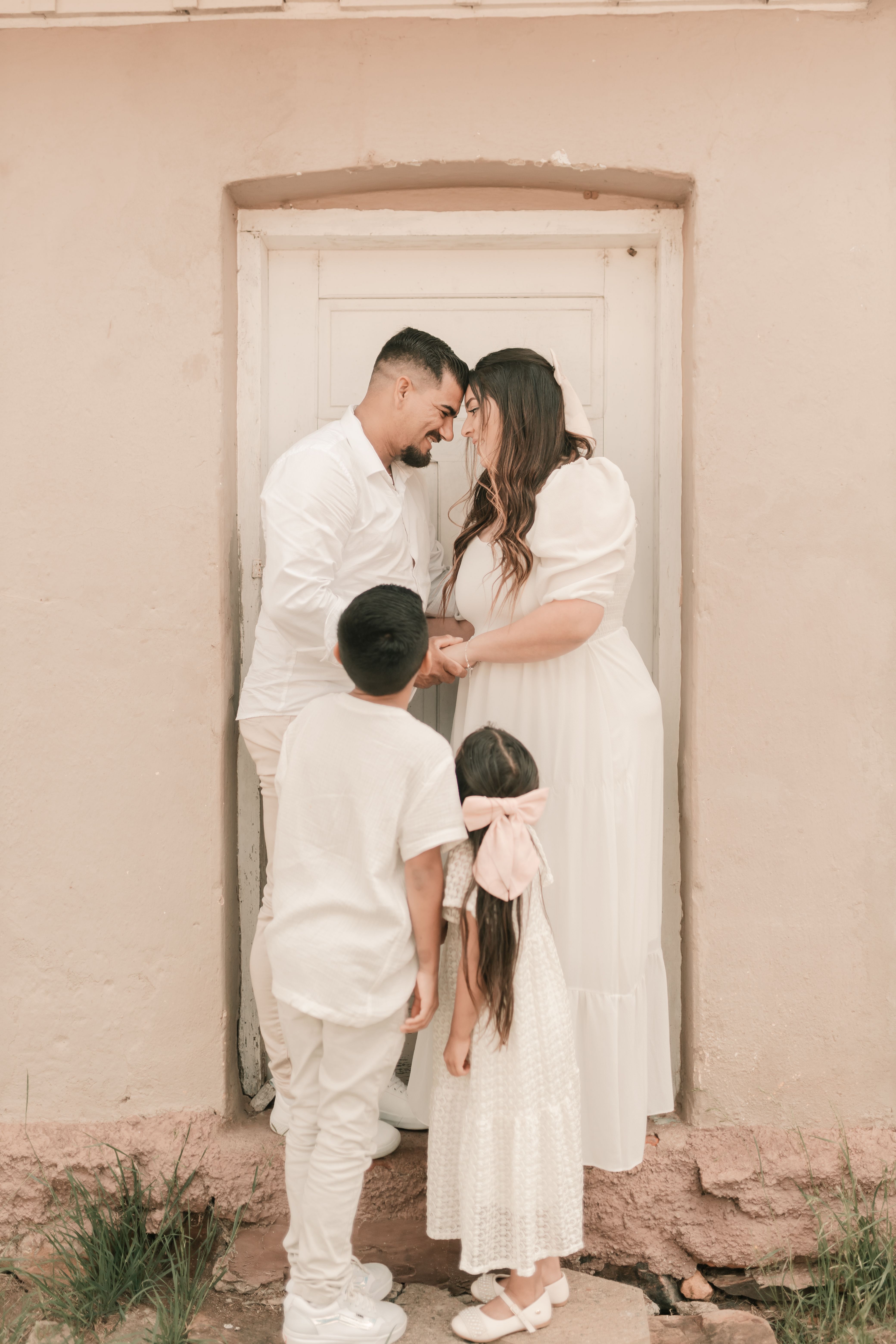 A family of four shares a tender moment in a serene outdoor setting.