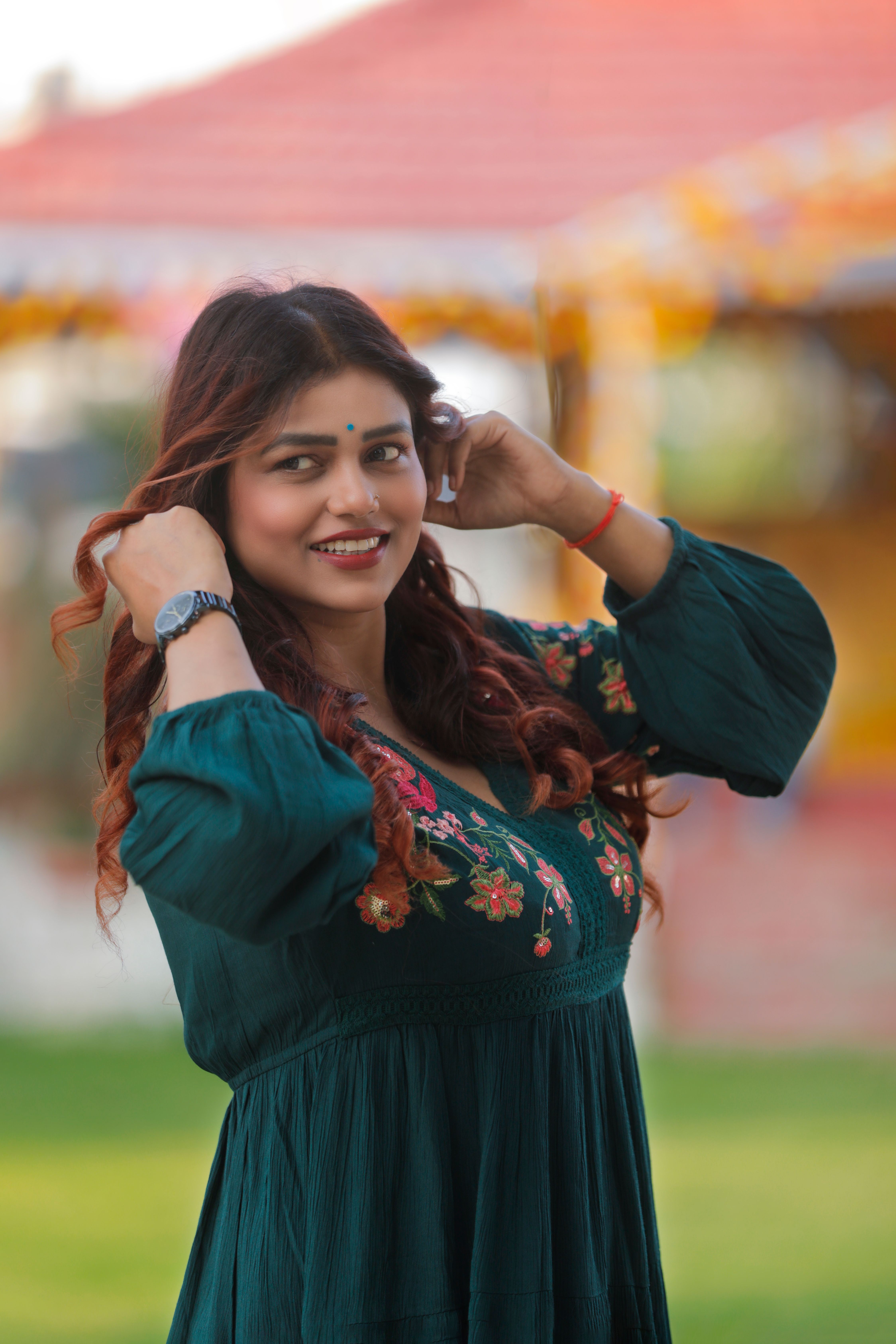 Chic portrait of a smiling woman in a green dress outdoors.