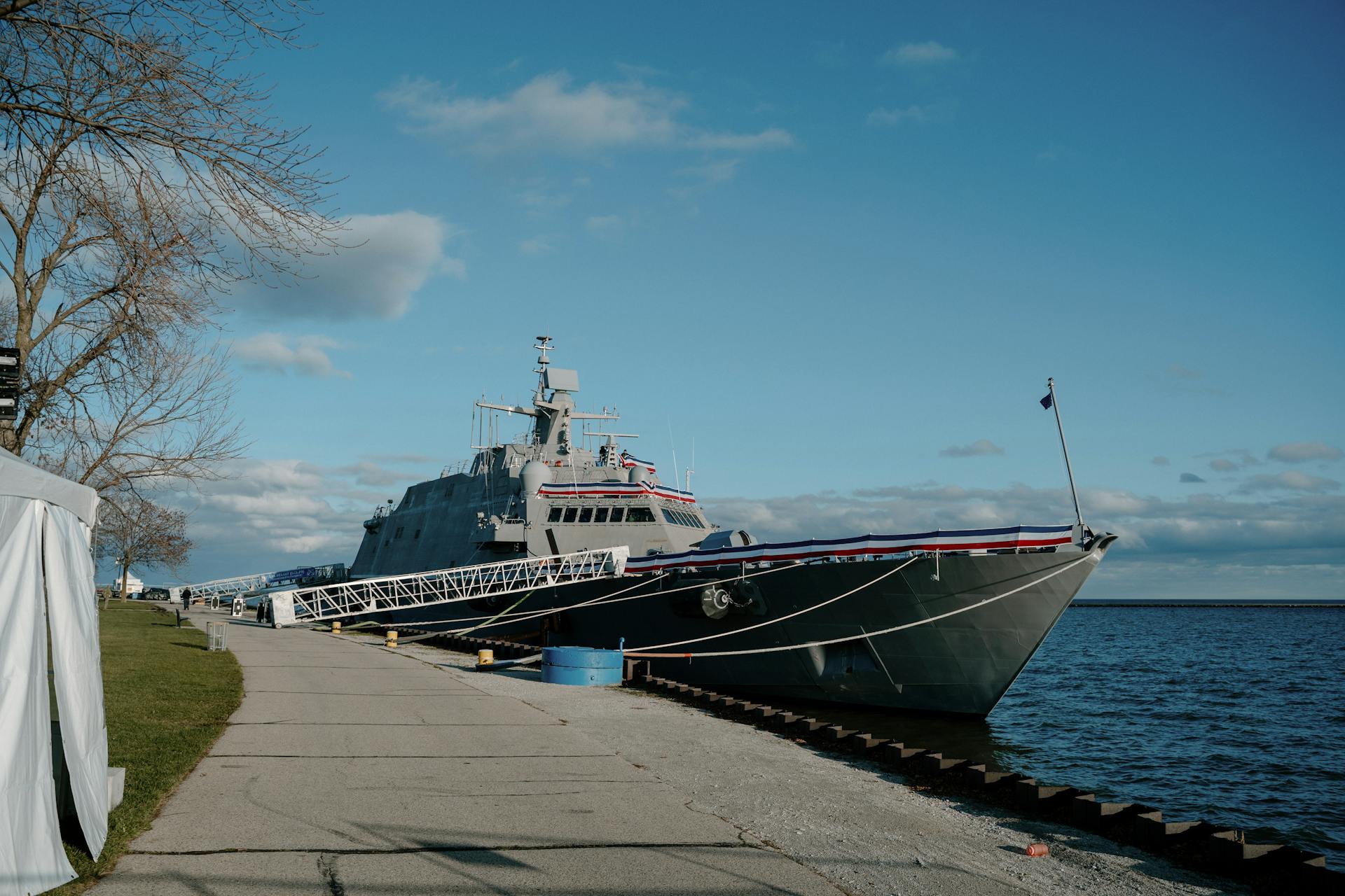 A Littoral Combat Ship docked by the lakeside in Milwaukee, Wisconsin under a clear blue sky.