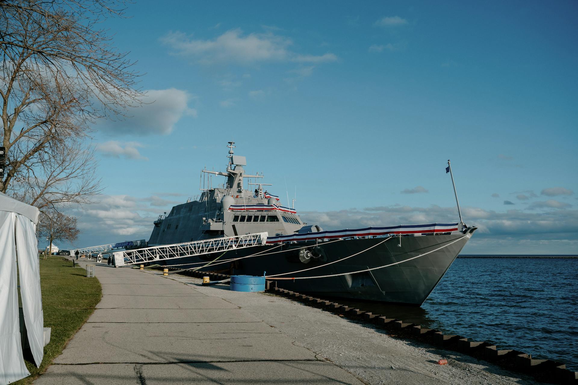 A large naval ship docked at Milwaukee's waterfront under a clear sky.