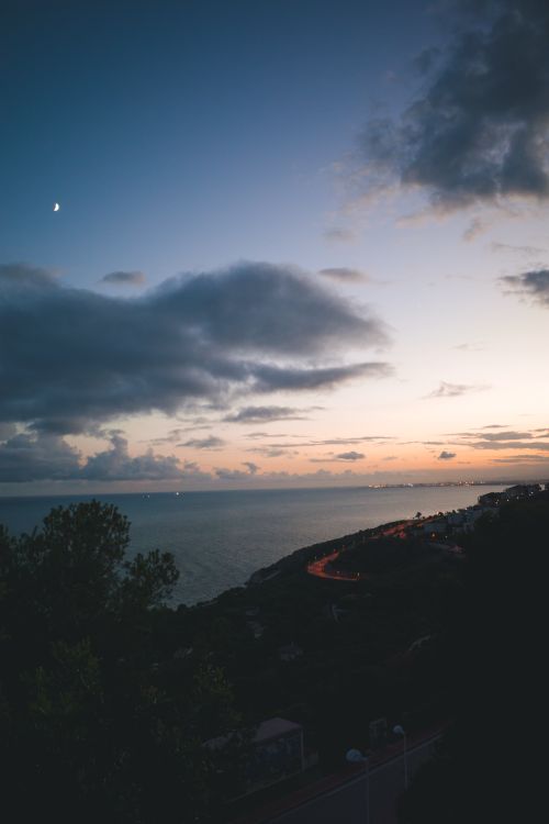 Free Dramatic sunset view over the coastline of Benicàssim, showcasing vibrant colors and serene seascape. Stock Photo