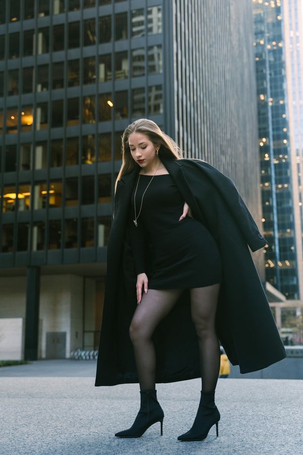 Woman in black wool coat over satin slip dress