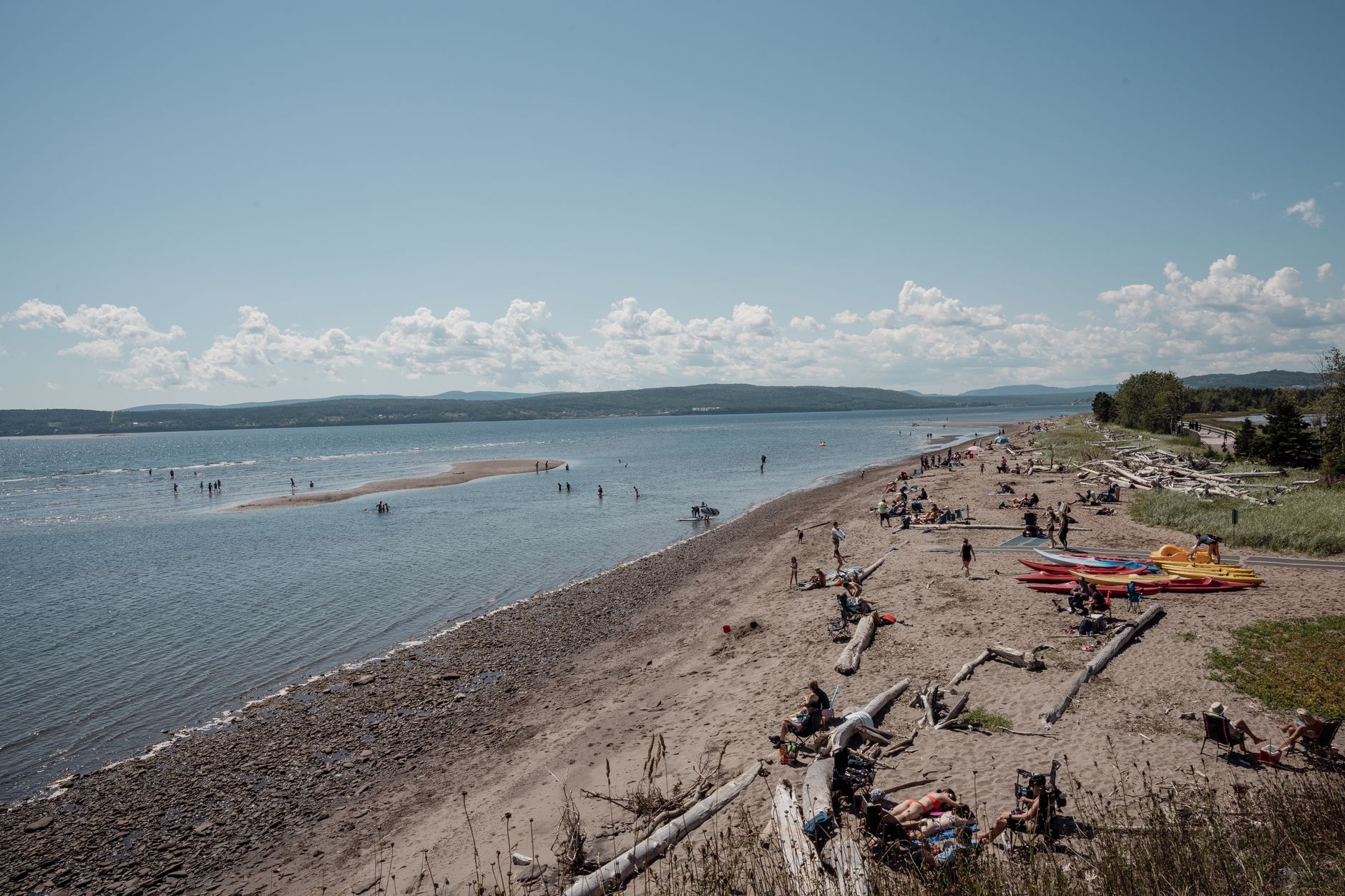 A lively summer day at the beach in Gaspé, Quebec, with people enjoying the water and sun.
