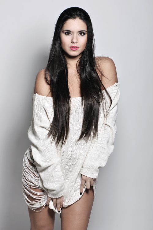Free Portrait of a stylish woman wearing a distressed white sweater against a plain background. Stock Photo