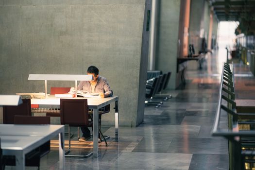 A man absorbed in reading at a contemporary library in Mexico City, bathed in natural light.