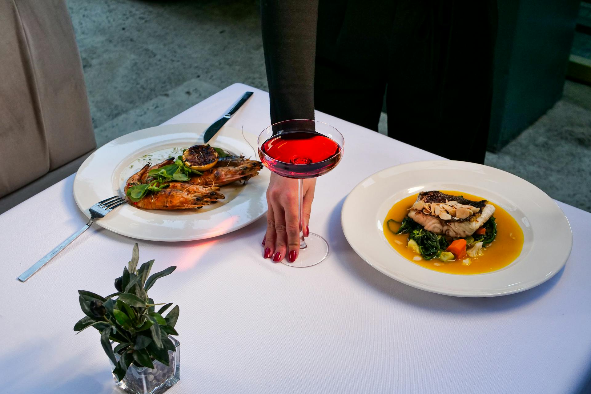 Luxurious food presentation with grilled seafood and a red cocktail in a Turkish restaurant setting.