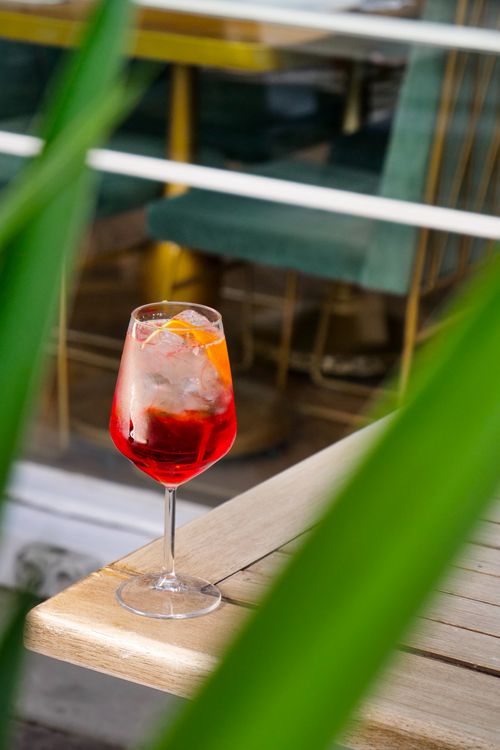 Free Chilled aperitif cocktail with orange slice served on a wooden table in a stylish outdoor café setting. Stock Photo