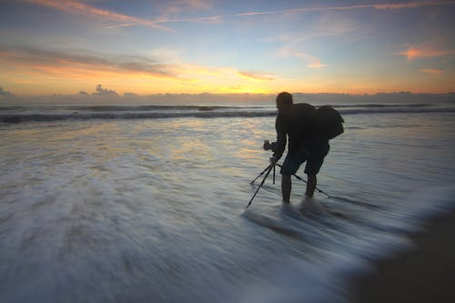 бесплатная Человек фотографирует океан во время золотого часа Стоковое фото