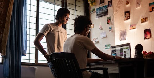 Uomo Che Indossa La Camicia Girocollo Bianca Che Si Siede Sulla Sedia Nera Mentre Si Utilizza Il Computer Portatile