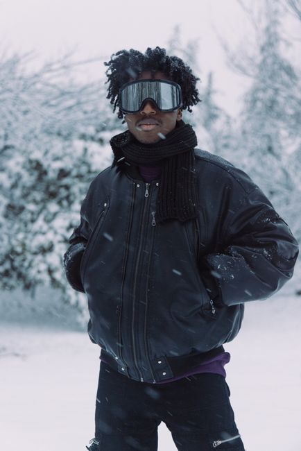 Fashion model poses in winter attire amidst a snowy outdoor setting, showcasing style and warmth.