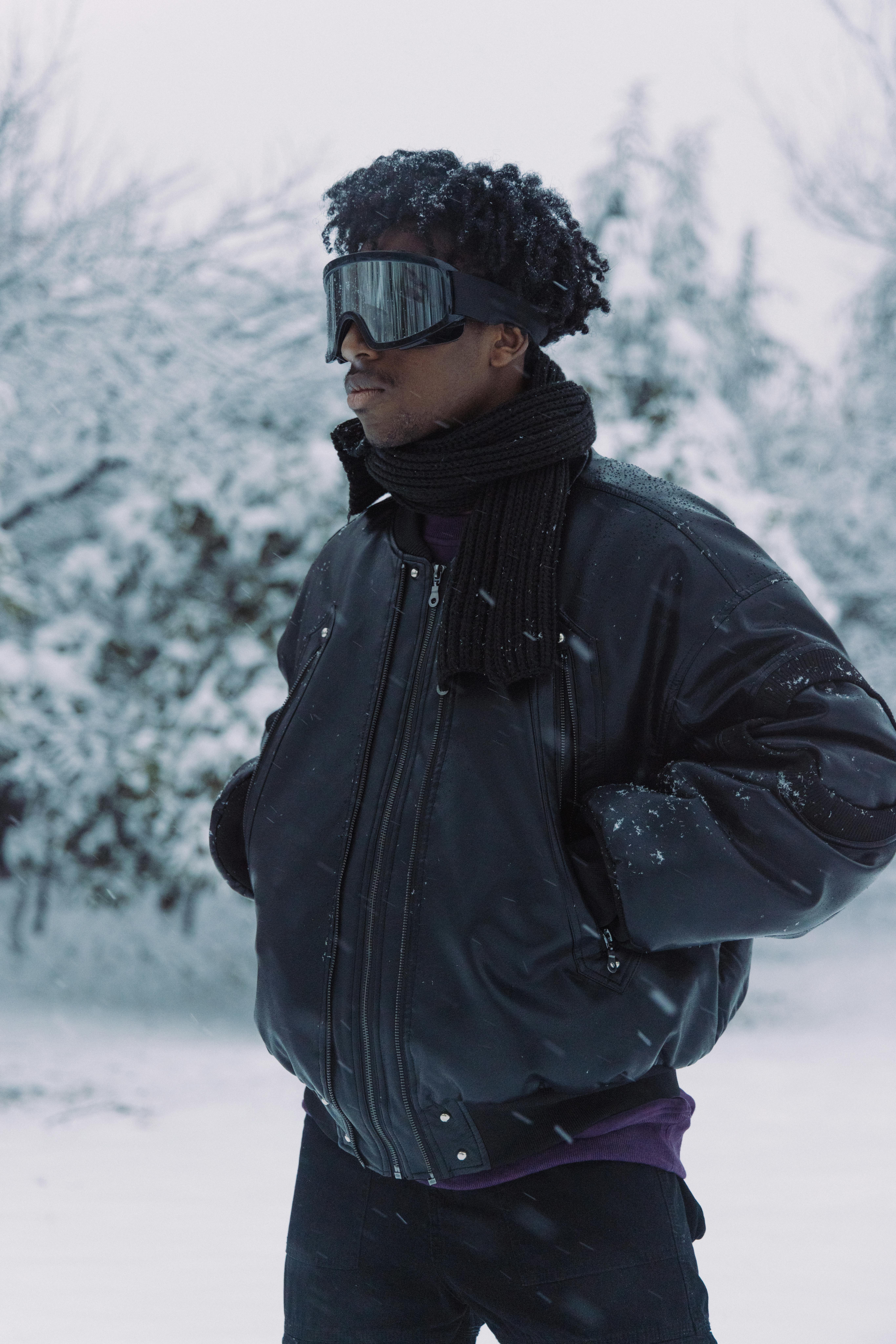 Man in winter attire posing in snowy Shanghai landscape, showcasing urban winter fashion.