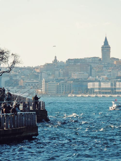 Free Scenic view of Galata Tower and Bosphorus with people fishing along the shore in Istanbul. Stock Photo