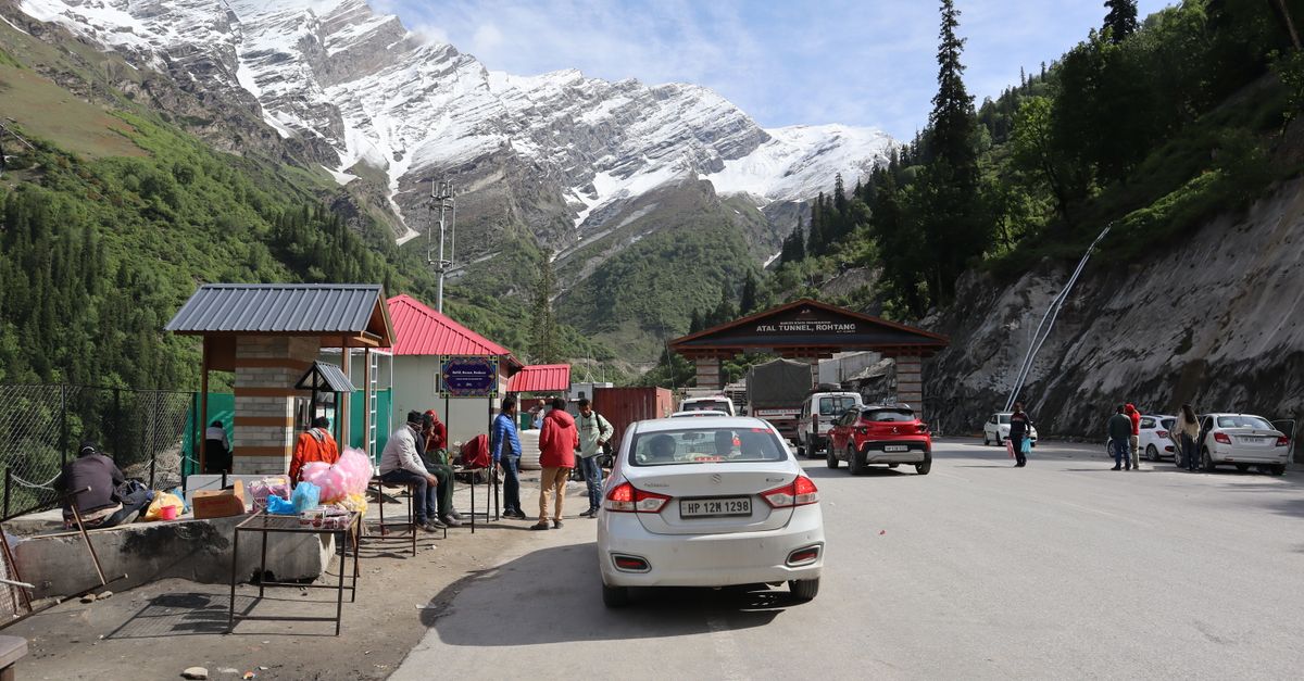 Bustling scene near Atal Tunnel, Ladakh with mountains, snow, and local vendors.