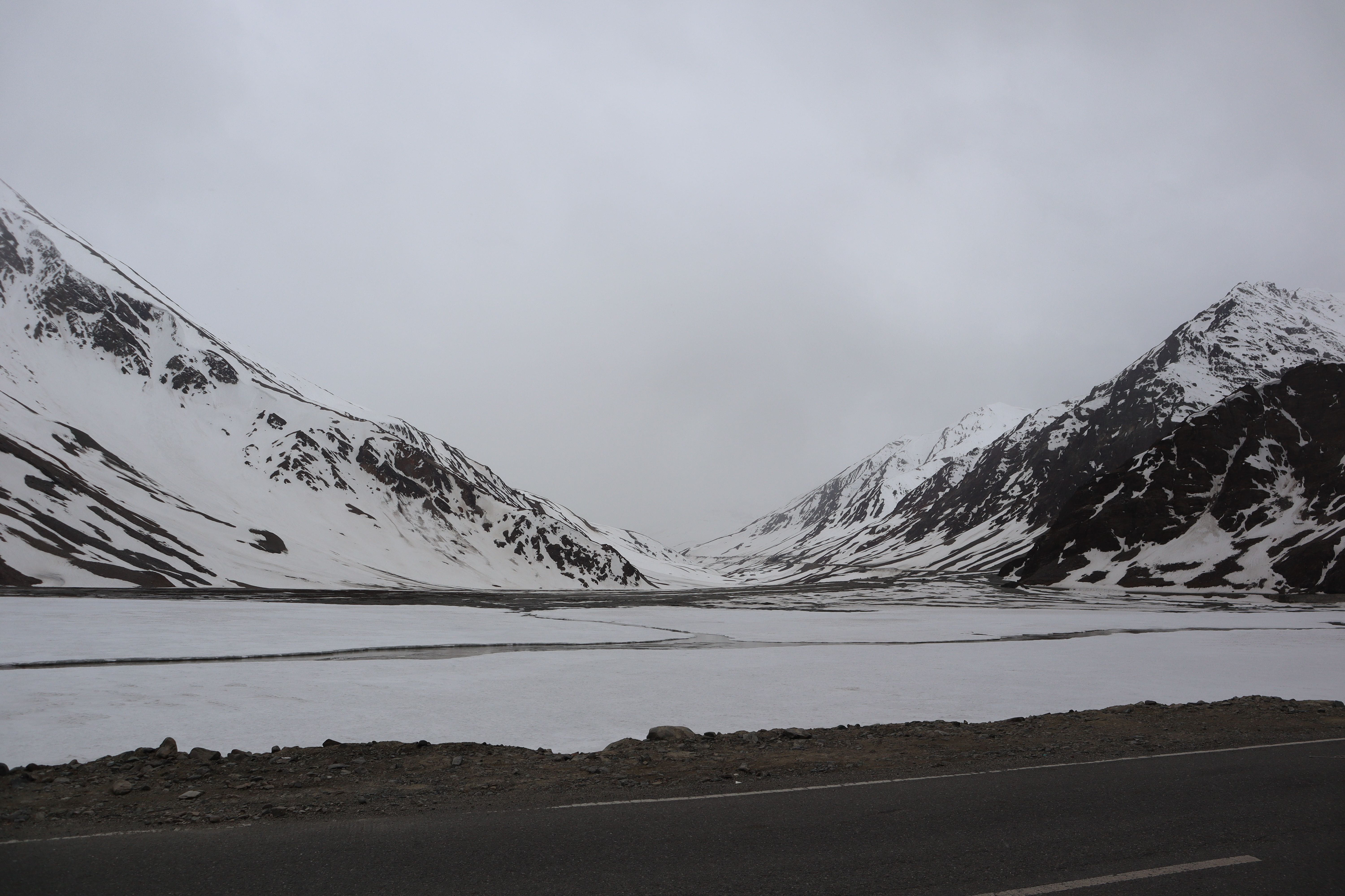 Serene snow-covered mountains and frozen lake in Ladakh, India, showcasing stunning winter scenery.