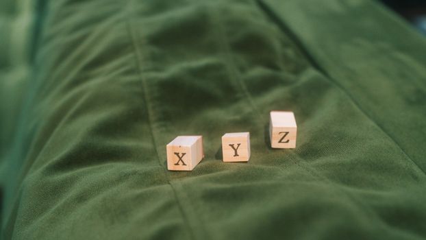 Wooden blocks with letters X, Y, Z on green fabric background.