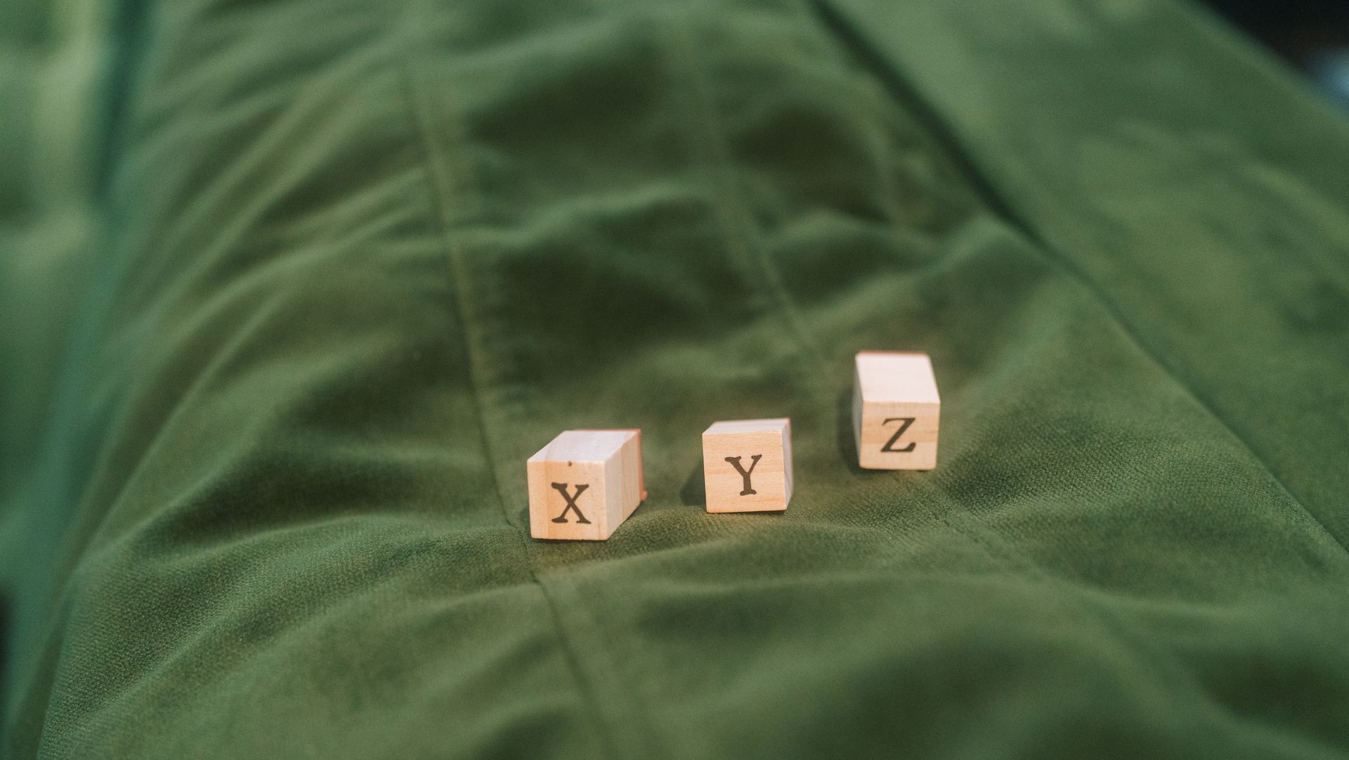 Wooden blocks with letters X, Y, Z on green fabric background.