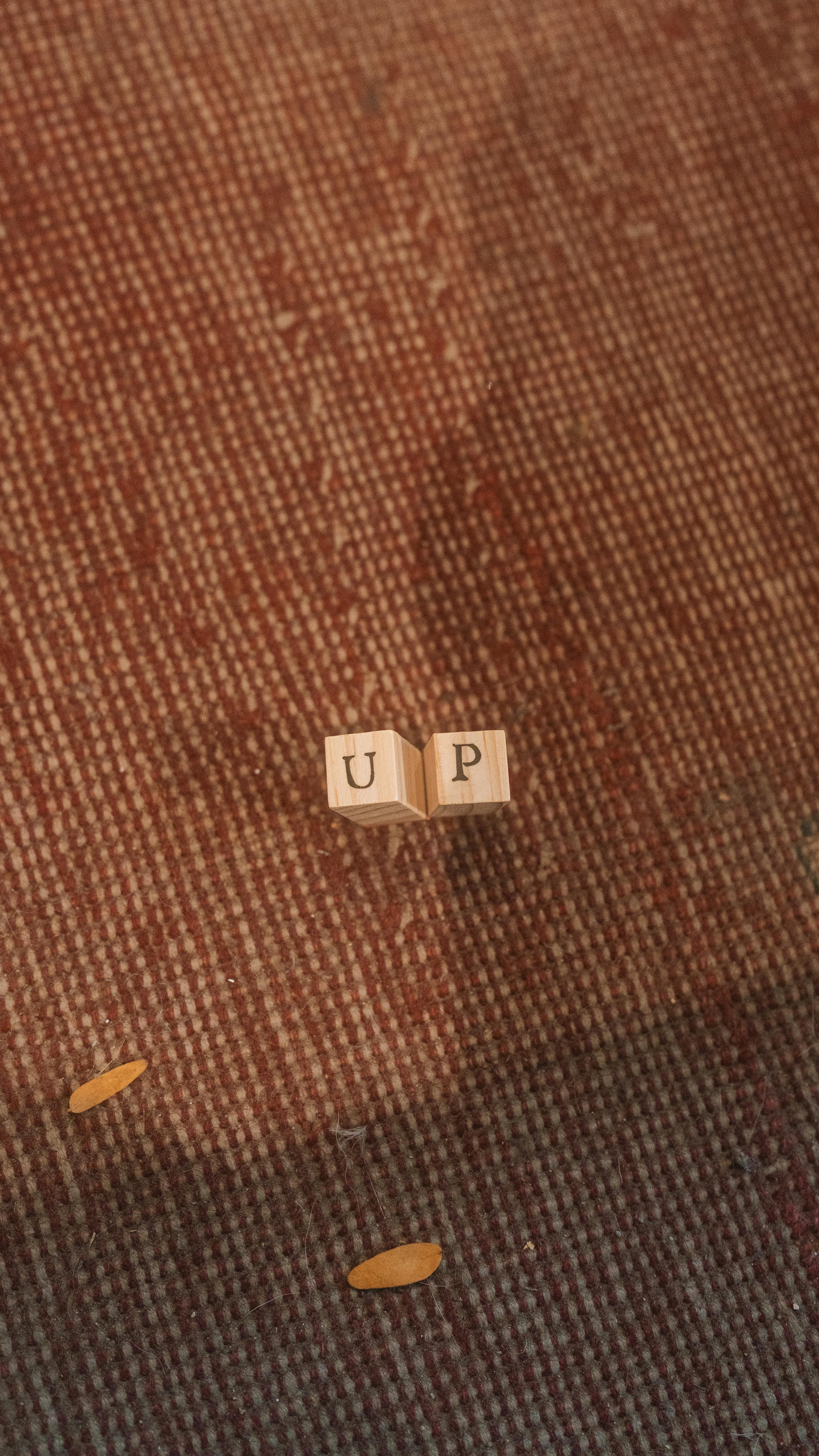 Kostenlos Holzklötze bilden das Wort „UP“ auf einem strukturierten roten Teppich. Stock-Foto