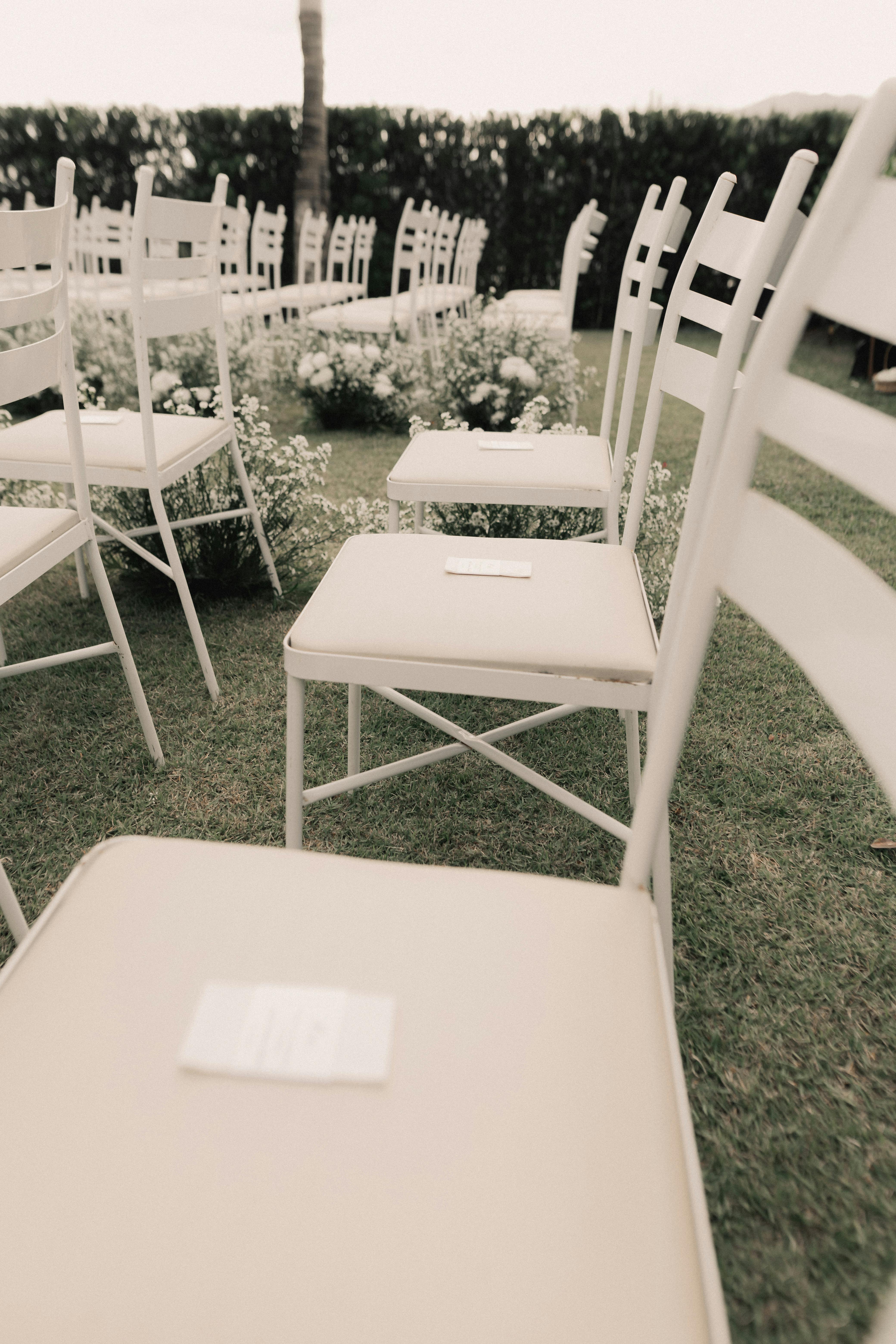 A serene setup for an outdoor wedding ceremony with white chairs and floral decor.