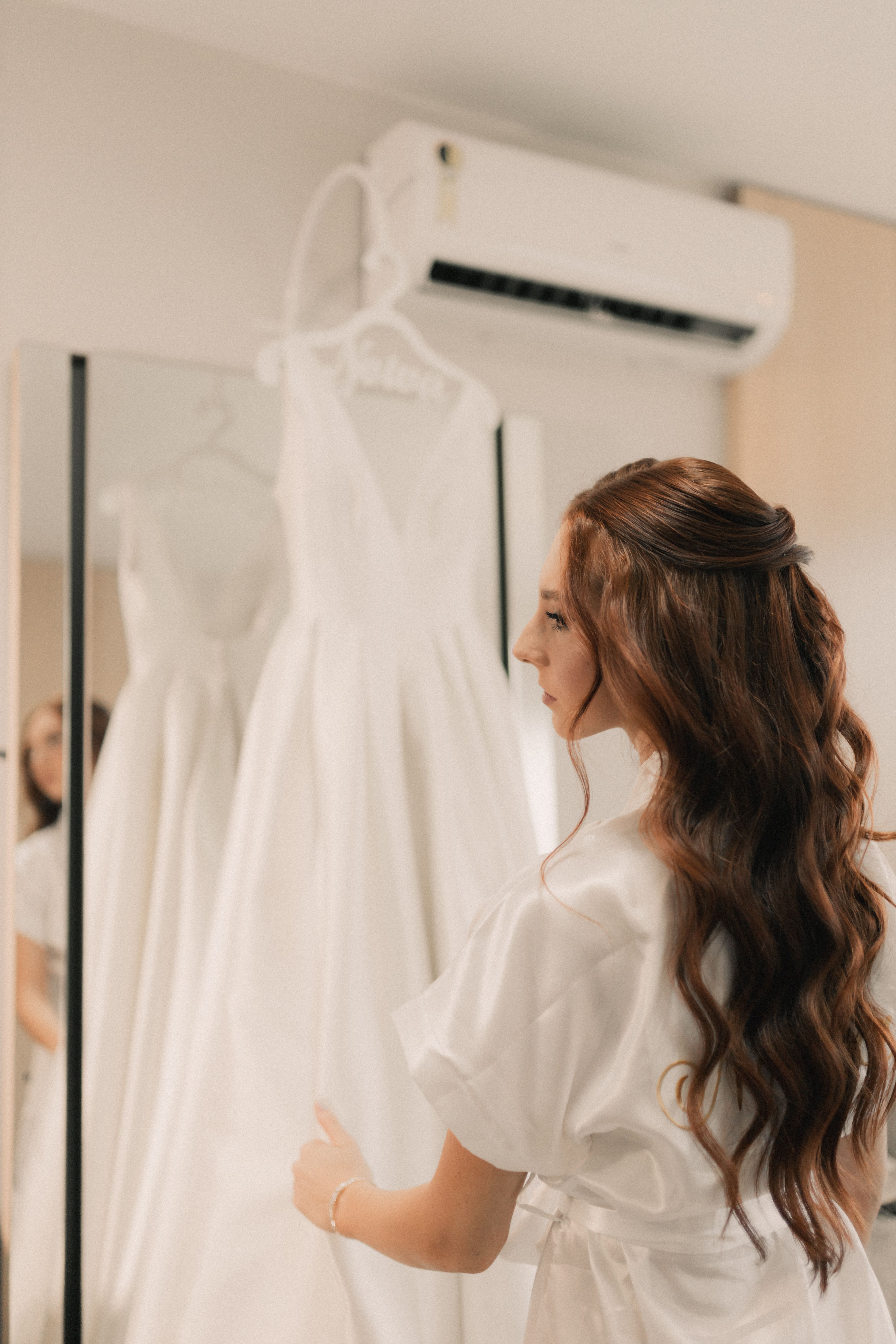 A bride admires her wedding gown in the mirror, readying for her special day.
