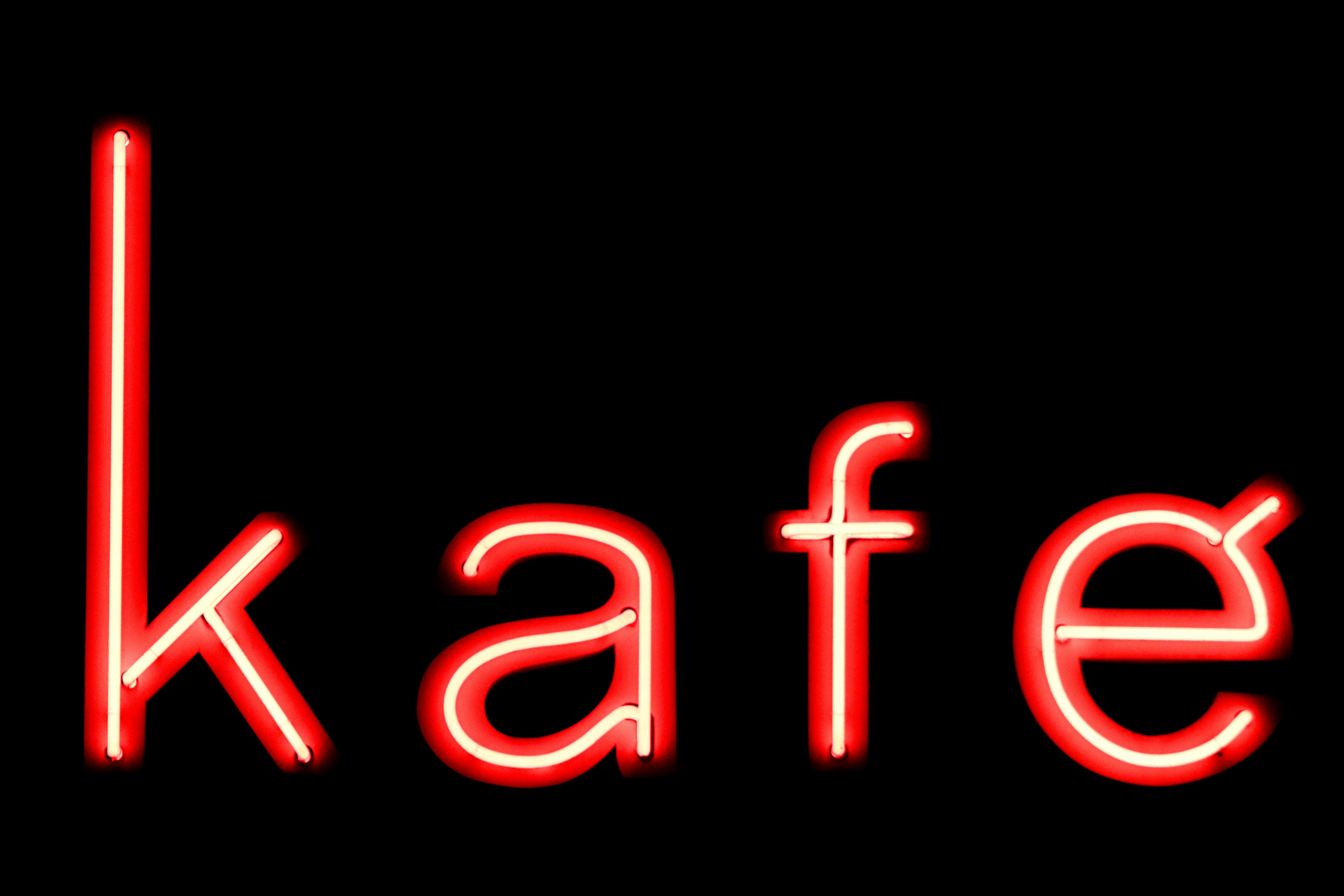 grátis Placa de neon vermelha "kafe" brilhando intensamente contra fundo preto. Foto profissional