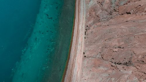 Free Stunning aerial shot of a desert coastline meeting turquoise ocean waters. Stock Photo