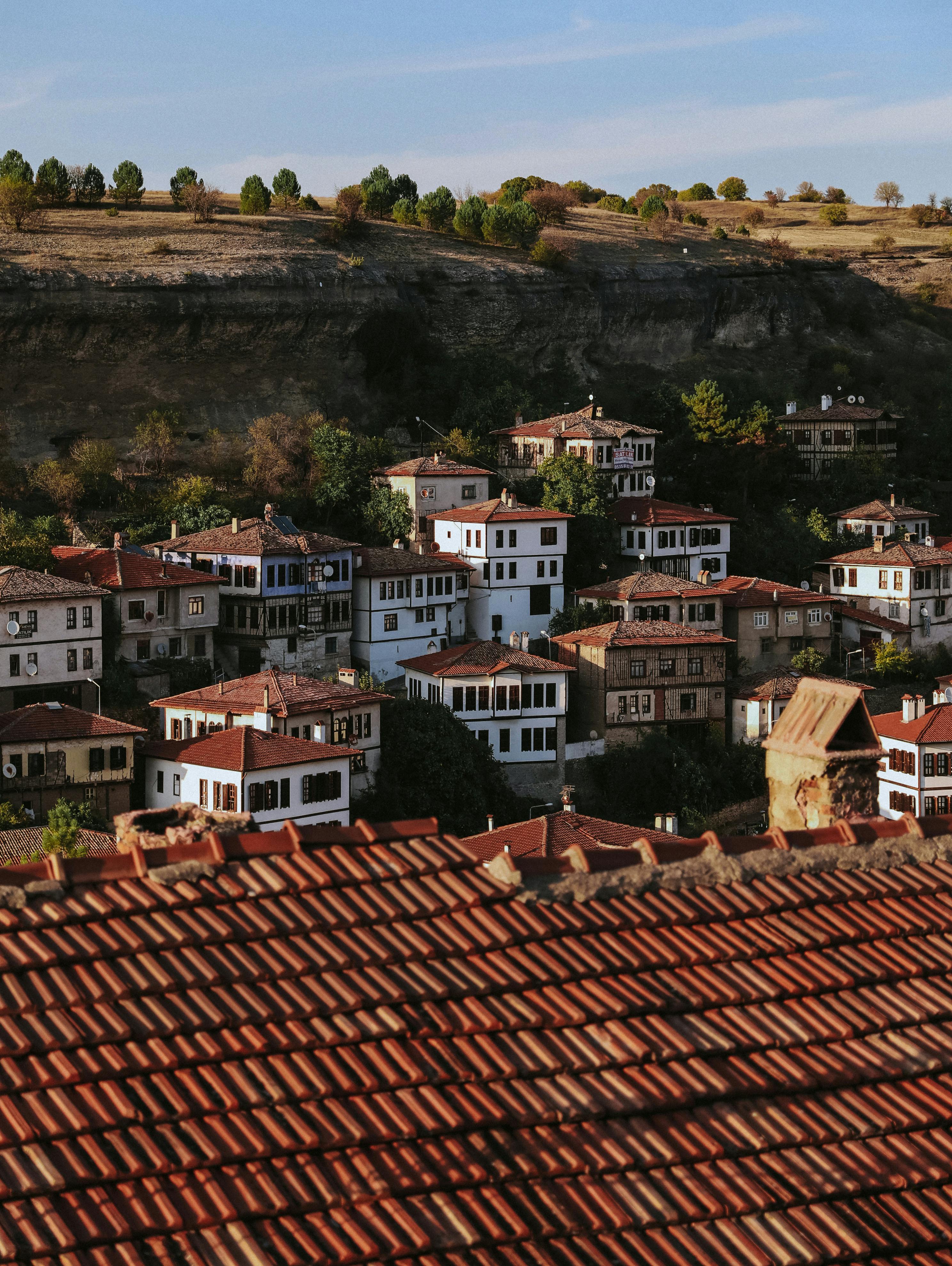 A picturesque view of a traditional Ottoman village with red-tiled roofs and lush surroundings.