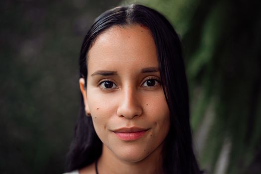 Close-up portrait of a young woman with natural expression and outdoor background.