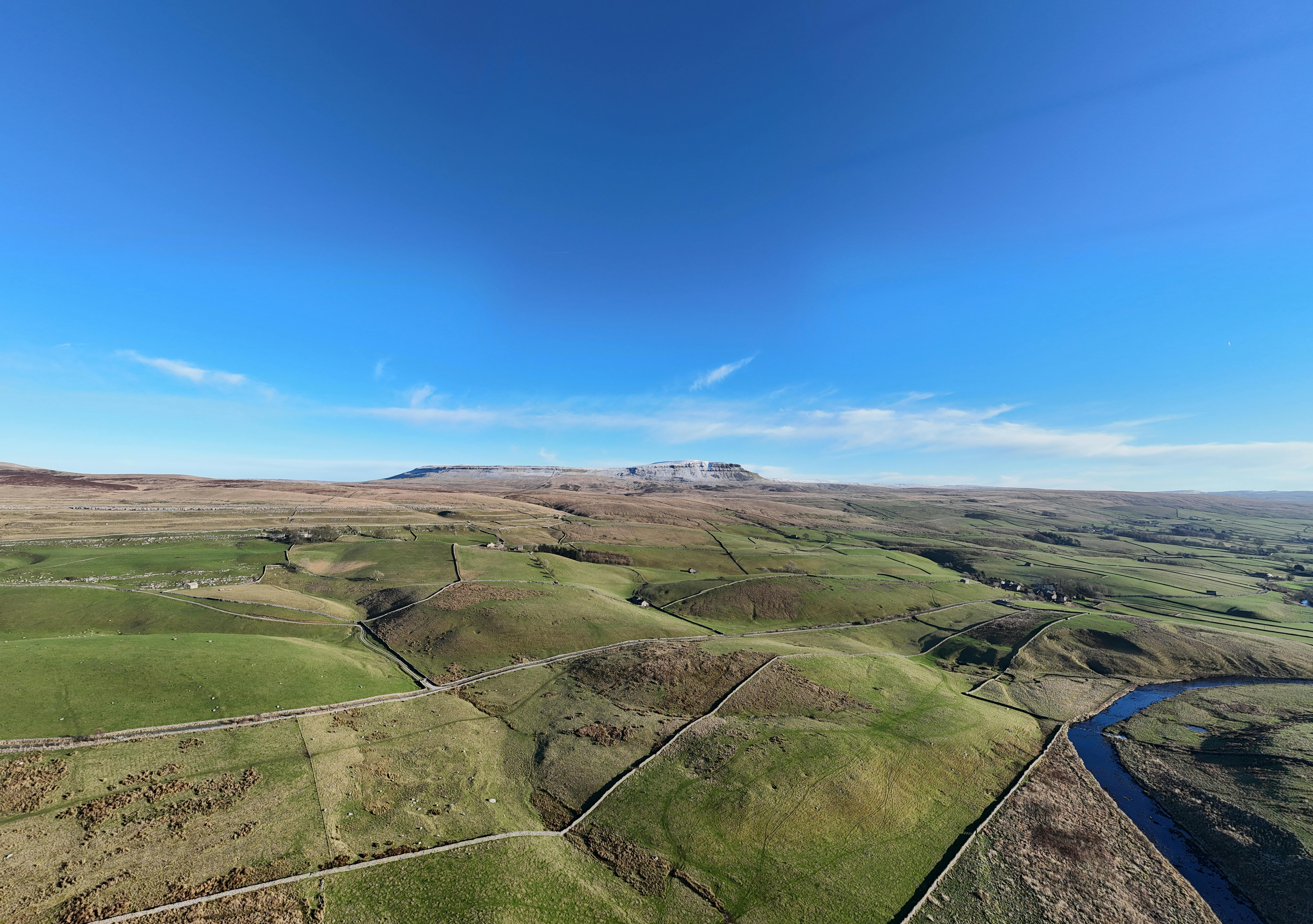 Stunning aerial view of Yorkshire Dales National Park showcasing green fields and clear blue sky.