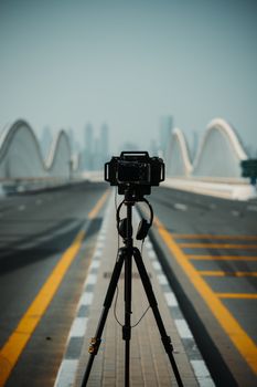 Photographer's camera setup on Meydan Bridge with Dubai skyline in the background.
