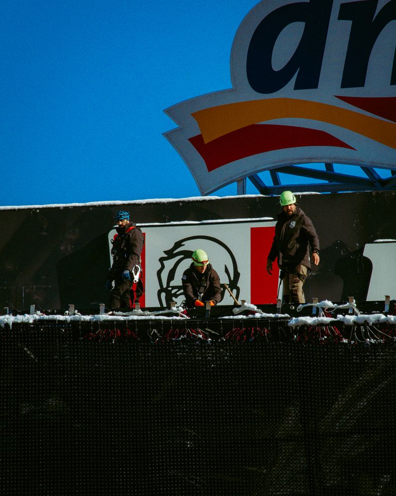 Construction workers in protective gear setting up a structure outdoors