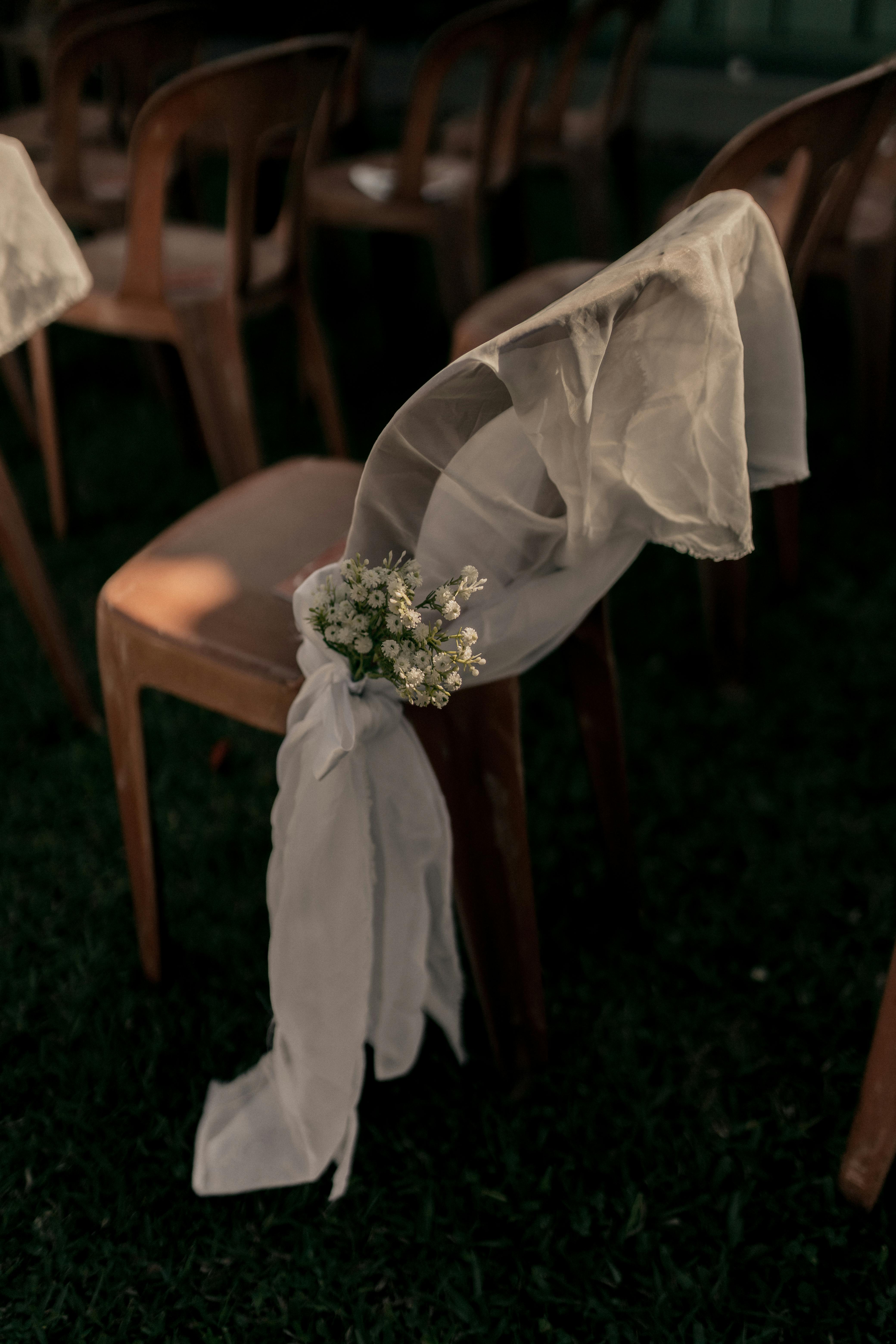 A beautifully decorated chair with white flowers at an outdoor wedding event.