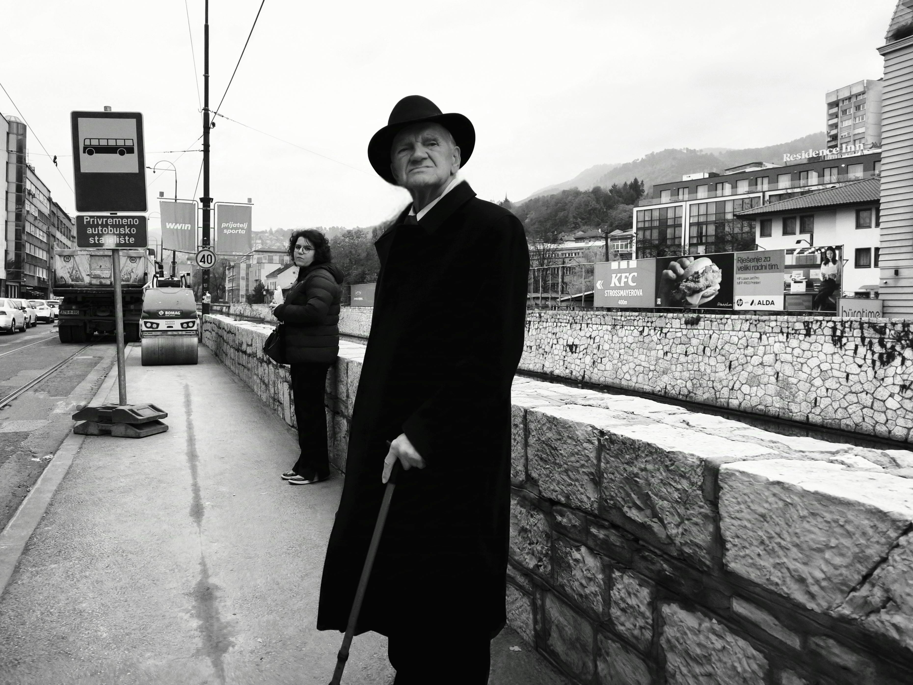 Black and white photo capturing daily life on a bustling street in Sarajevo, Bosnia.