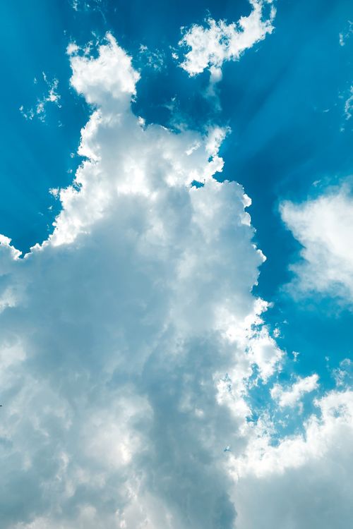 Free A striking view of tall clouds illuminated by sunlight against a vivid blue sky, offering a sense of wonder. Stock Photo