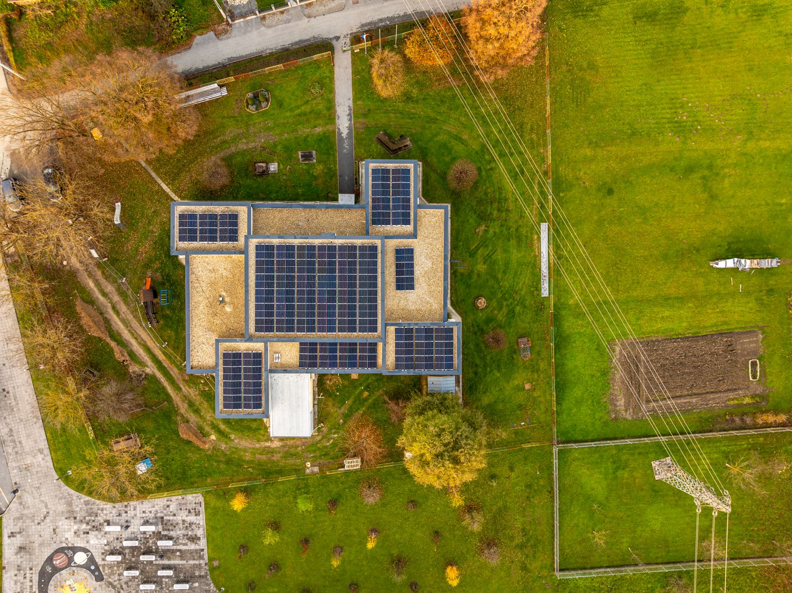 Aerial view of a building with a large solar panel array in a green landscape