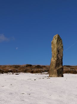 Monolithic stone standing upright on a snowy field under a clear blue sky.