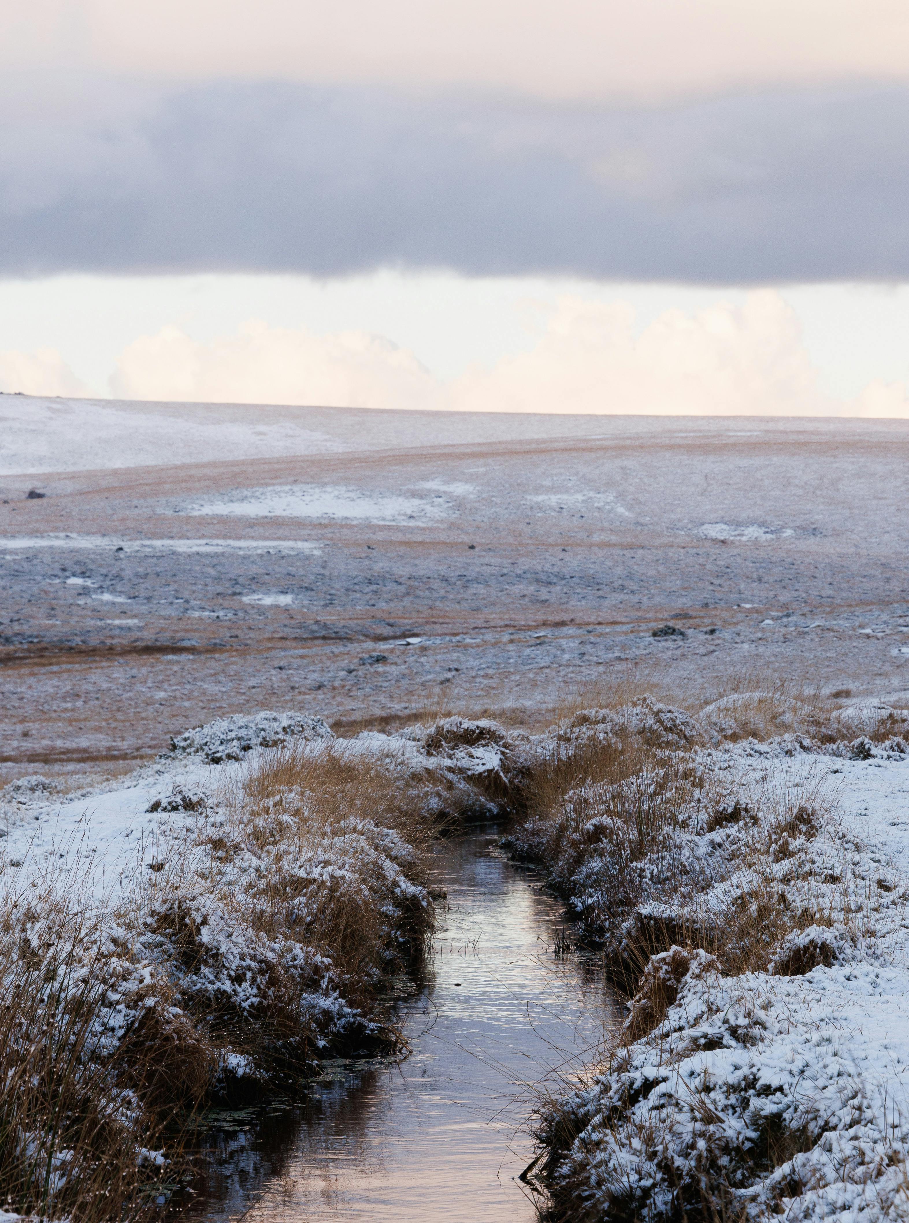 Serene snow-covered landscape with a flowing stream during wintertime.